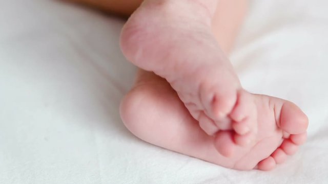 feet of a newborn lying on white bed at home