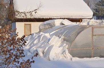 A greenhouse and a house in the garden.
The end of winter. The snow began to melt. A thick layer...