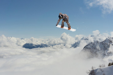 Naklejka na ściany i meble Snowboarder jumps in mountains, winter extreme sport.