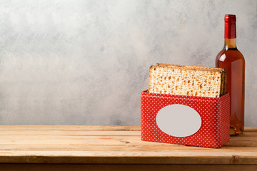 Passover celebration concept with matzoh and wine bottle on wooden table over bright background with copy space