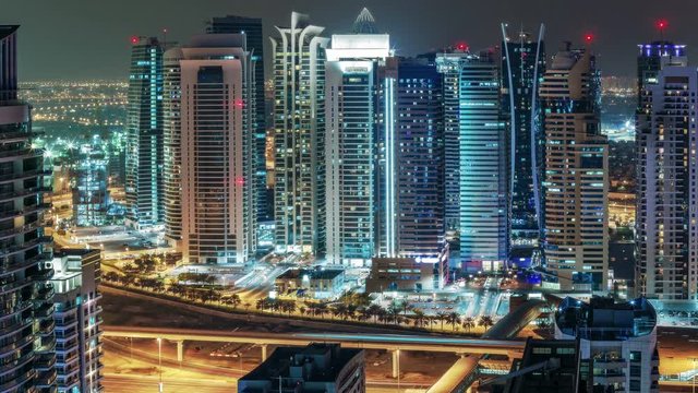 Fantastic cityscape of Dubai Marina, UAE, by night. Scenic rooftop view over illuminated residential skyscrapers and highways. 4K time lapse. Travel and and architecture background.