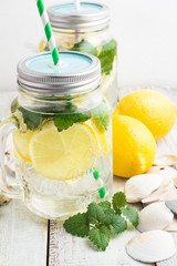 Fototapeta premium Water with lemon and mint in a glass mug with a lid and a straw.
