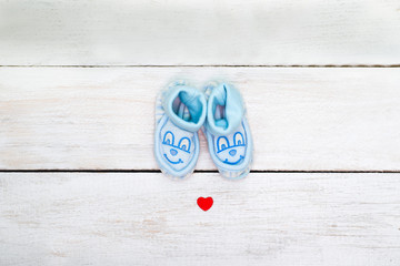 Blue booties for the boy on a white wooden background. view from above