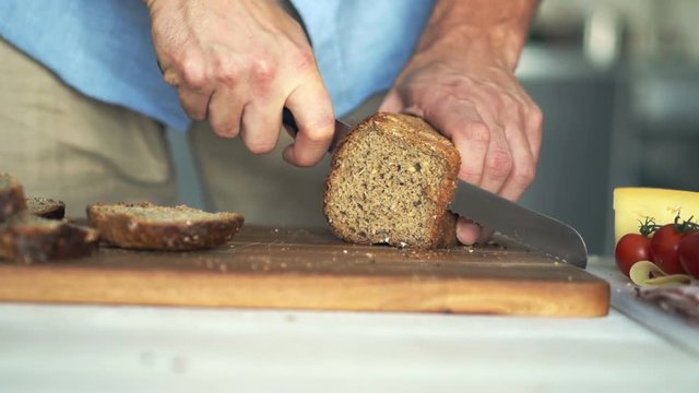Male hand slicing wholemeal bread, super slow motion 
