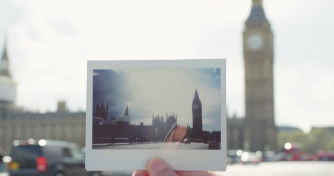 Close up hand holding polaroid photograph in front of Big Ben Landmark travel concept