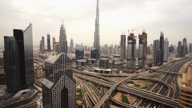 Spectacular daytime skyline of downtown Dubai, UAE. Scenic aerial view of famous highway intersection with dense traffic at dusk. Transportation and travel background
