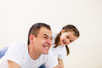 Obraz premium Smiling father carrying on his shoulders his little daughter isolated on white background
