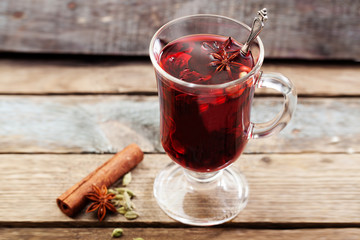Mulled wine with a badge and cardamom in a glass on a wooden table top