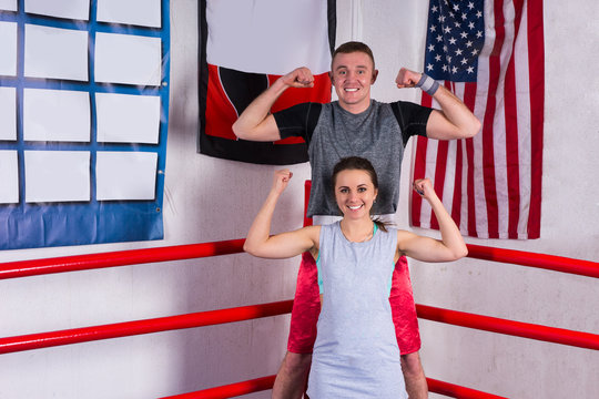 Couple in sportswear standing in a boxing pose in regular boxing ring