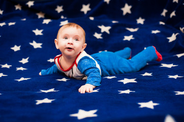Child 6 months old and smiling at home on a blue blanket of the starry sky