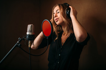 Female singer in headphones against microphone