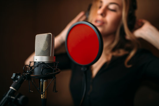 Female singer in headphones against microphone