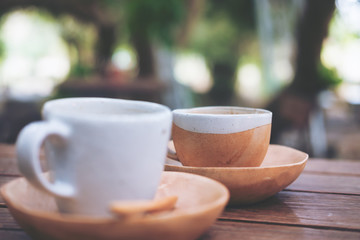 Two cups of hot coffee on vintage wooden table with blur nature background 