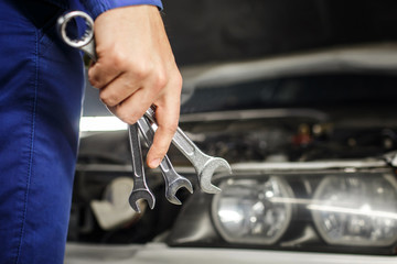 Hand of car mechanic with wrench. Auto repair garage.