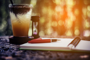 pen and fruit juice on the desk, open a blank white notebook on table