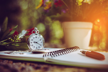pen, packet watch and rose  on the desk, open a blank white notebook on table