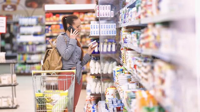 Woman talking on the phone at a supermarket near food