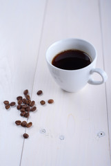 Coffee in a white cup on a white background. Coffee beans on the table