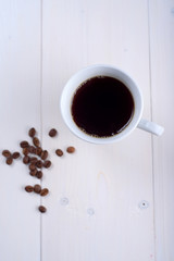 Coffee in a white cup on a white background. Coffee beans on the table
