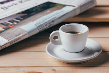 cup of coffee with newspaper in background