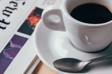 Cup of coffee with newspaper in background