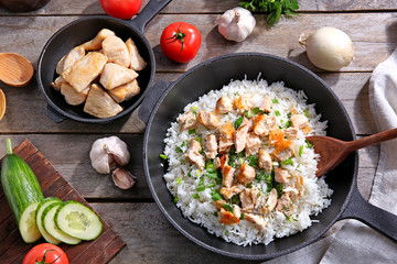 Frying pan with chicken and rice on kitchen table