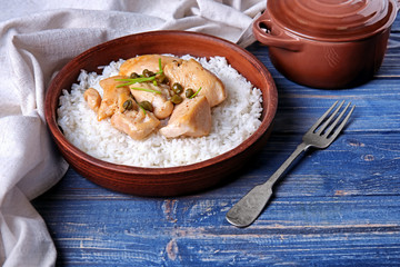 Bowl with chicken and rice on wooden table