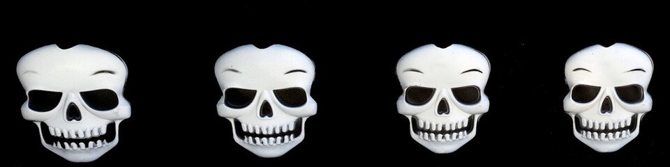 Four Halloween skulls on a black background. Horizontal.