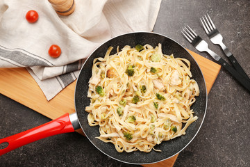 Frying pan with delicious chicken Alfredo on kitchen table