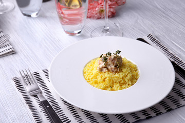 Plate with rice and chicken on table