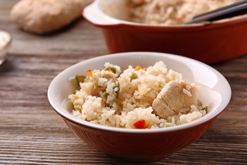 Delicious rice with chicken and vegetables in plate on wooden table