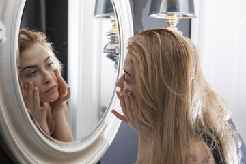 Adult woman checking her face in mirror