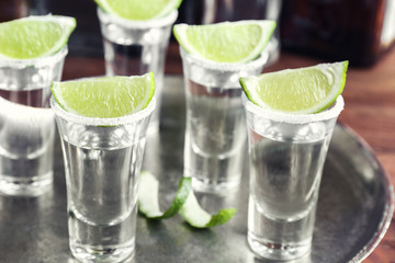 Tequila shots with juicy lime slices and salt on tray