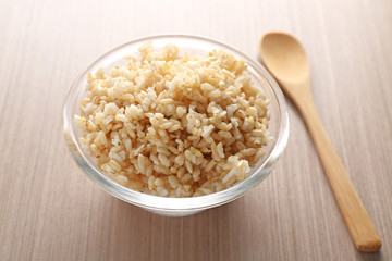 Glass bowl full of brown rice on wooden table