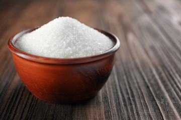 Bowl full of sugar on wooden background