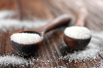 White sand sugar in spoons on wooden background