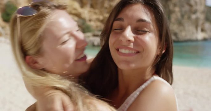Best friends hugging two cute girl teenagers giving kiss on cheek woman on tropical beach summer vacation 