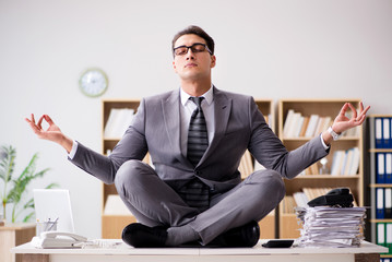 Young businessman meditating in the office - Powered by Adobe