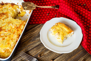 Useful, hearty and delicious dinner or lunch, potato casserole with chicken, cheese, mayonnaise, egg and spices on a wooden background 