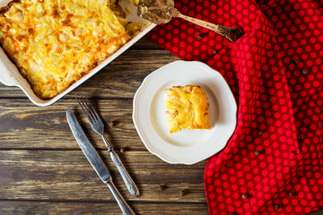 Useful, hearty and delicious dinner or lunch, potato casserole with chicken, cheese, mayonnaise, egg and spices on a wooden background 