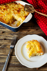 Useful, hearty and delicious dinner or lunch, potato casserole with chicken, cheese, mayonnaise, egg and spices on a wooden background 