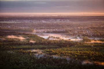 Dawn mist over the forest and village, Russia