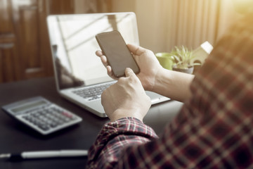 Obraz premium Side view shot of a man's hands using smart phone in interior, rear view of business man hands busy with tablets at office desk, young male student typing calculator at wooden table