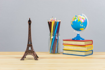 Eiffel tower statue and stack of book ,color pencil and globe on the school desk,knowledge school background education concept