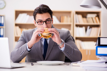 Fototapeta premium Hungry funny businessman eating junk food sandwich
