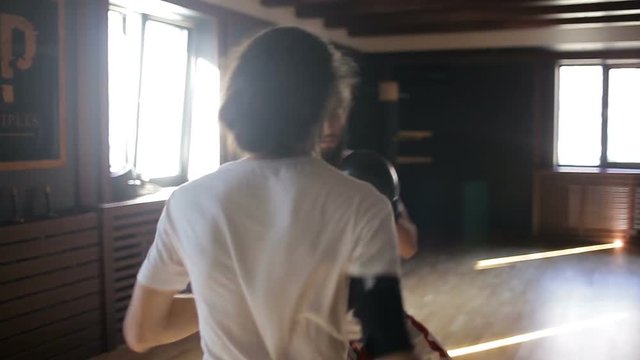 The twin brothers in boxing gloves sparring in the training hall. Chinese martial arts.