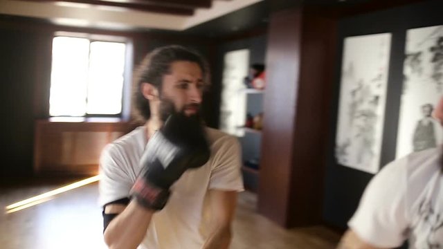 The twin brothers in boxing gloves sparring in the training hall. Chinese martial arts.