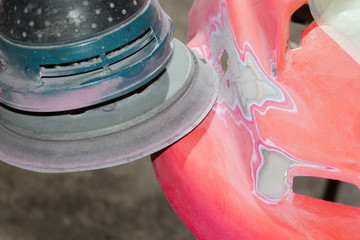 Work polishes the car body component, preparation before painting