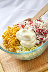 Chinese cabbage, sweet corn, surimi and mayonnaise in a glass bowl