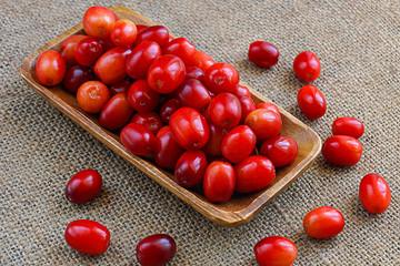 Cranberries, cornelian cherries in a wooden bowl on  burlap